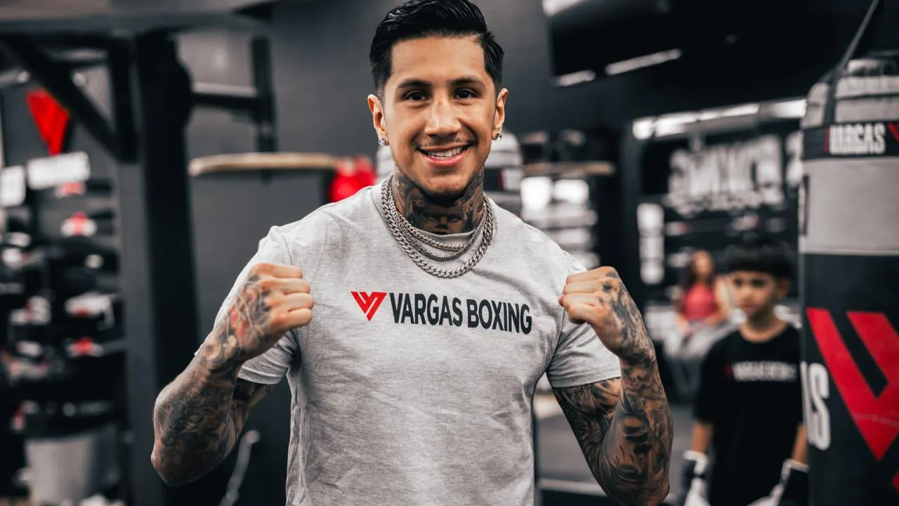 Smiling fighter wearing a Vargas Boxing shirt with fists raised.