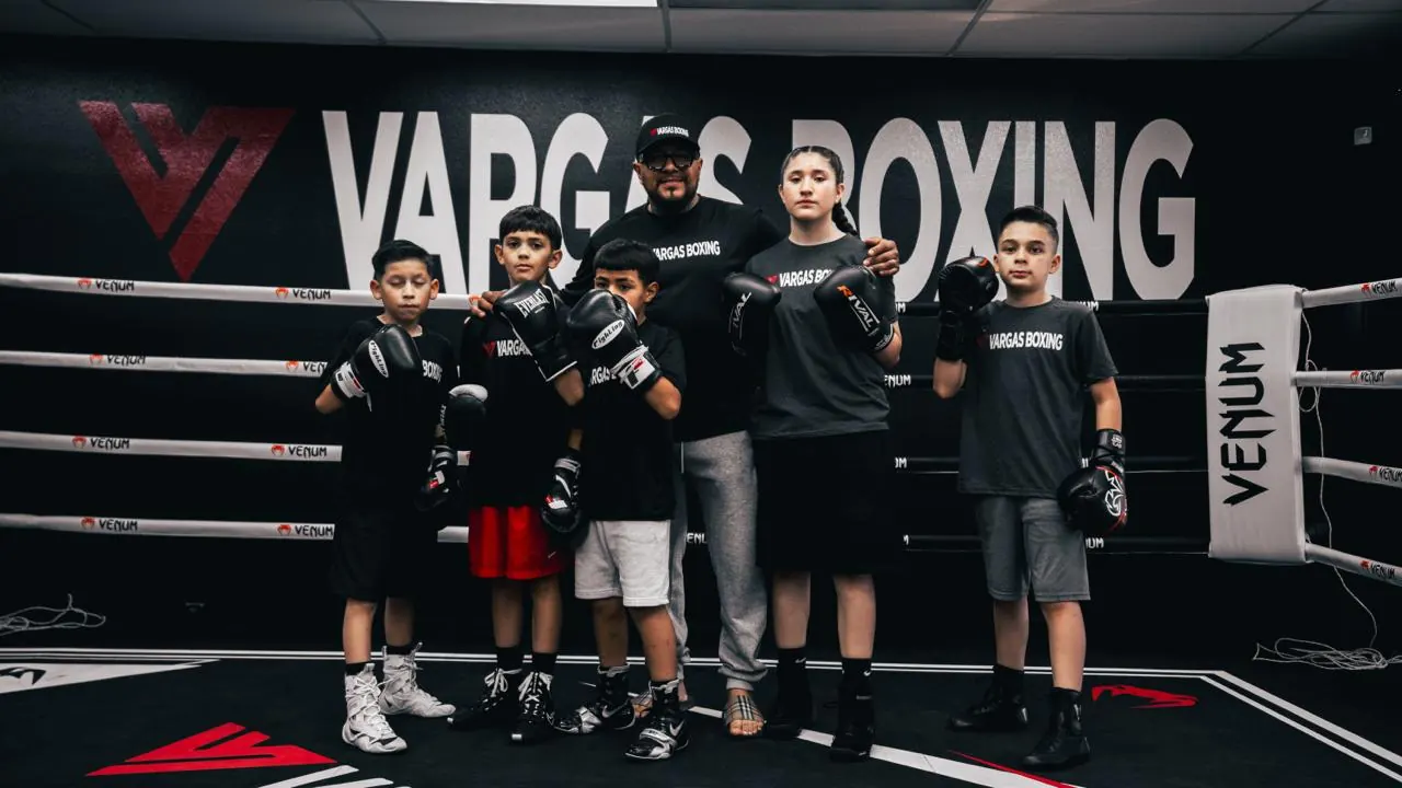 Vargas Boxing coach standing with youth boxers in the ring.